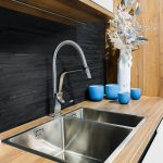 In a welldesigned kitchen, you will find a stainless steel sink elegantly placed on a beautifully crafted wooden counter, creating a perfect blend of functionality and aesthetics